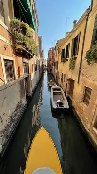 A yellow motorboat in a canal in Venice. Stock Photos
