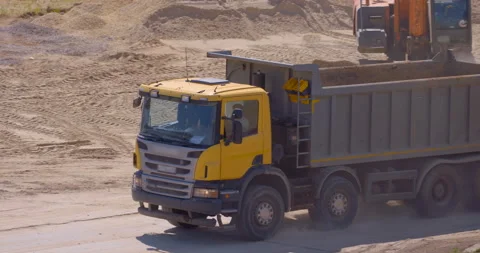 Yellow multi-axle truck driving on construction site  to load the earth Stock Footage 147635334