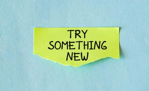 Yellow note on blue background with text TRY SOMETHING NEW, to encourage pe.. Stock Photos