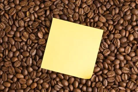 Yellow note paper on coffee beans background Stock Photos