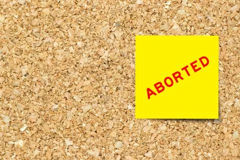 Yellow note paper with word aborted on cork board background with copy space Stock Photos
