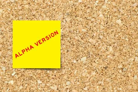 Yellow note paper with word alpha version on cork board background with copy  스톡 사진
