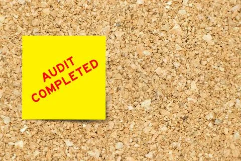 Yellow note paper with word audit completed on cork board background with c.. Stock Photos