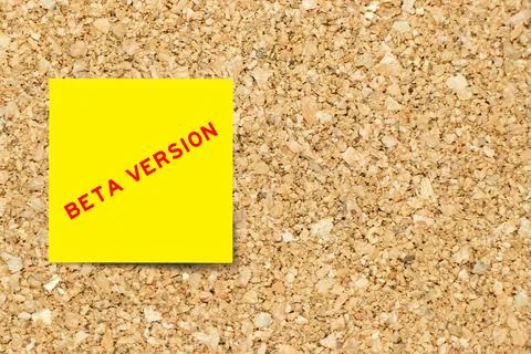 Yellow note paper with word beta version on cork board background with copy s Stock Photos