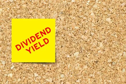 Yellow note paper with word dividend yield on cork board background with co.. Stock Photos
