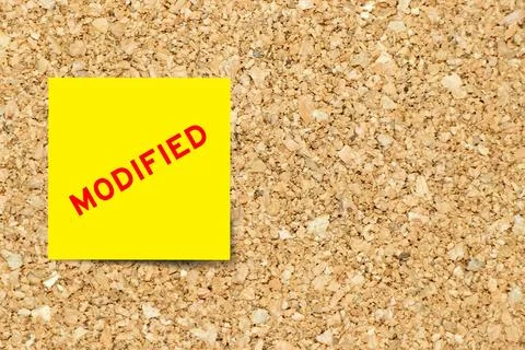 Yellow note paper with word modified on cork board background with copy space 写真素材