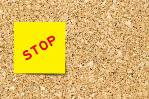 Yellow note paper with word stop on cork board background with copy space 写真素材