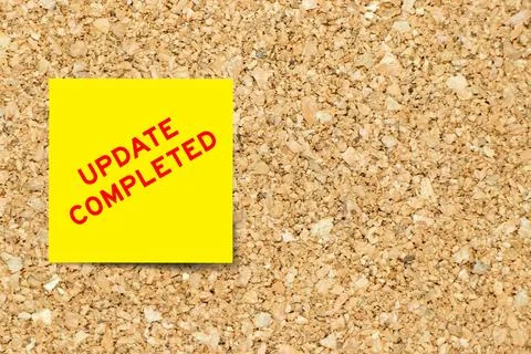Yellow note paper with word update completed on cork board background with .. 写真素材