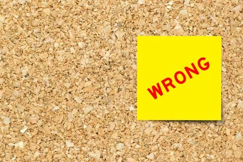 Yellow note paper with word wrong on cork board background with copy space Foto stock