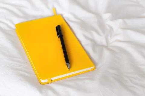 Yellow notepad on a bed Stock Photos