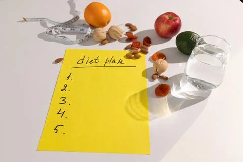 Yellow notepad with empty diet plan outline surrounded by fresh orange, apple 스톡 사진