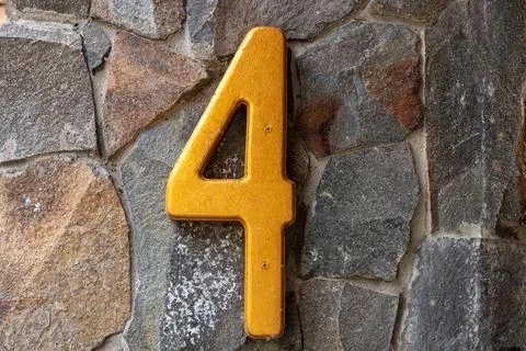 Yellow number four on a stone wall Stock Photos