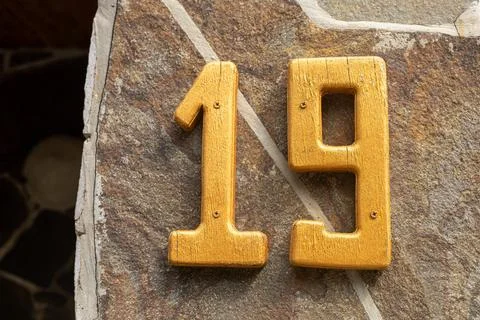 Yellow number nineteen on a stone wall Stock Photos