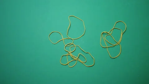 Yellow office rubber bands fall on a green surface Stock Footage 233209209
