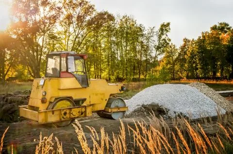 Yellow old machine for laying asphalt on the road in the morning at dawn . Stock Photos