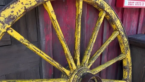 Yellow old wheel on the background of the red wall 11.04.22 Disneyland, Paris Stock Footage 179328347