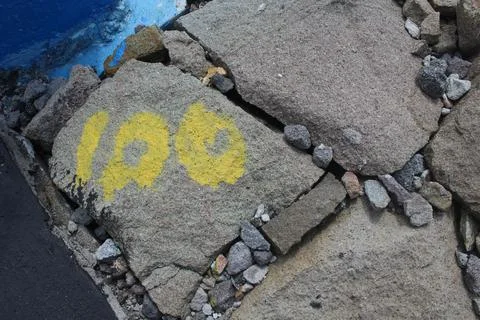Yellow one zero zero symbol on a dam rock Foto stock