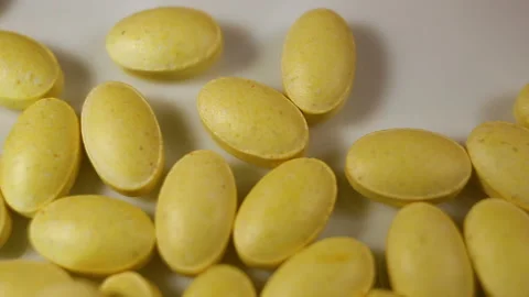 Yellow oval pressed tablets are swiped by hand. Close-up, real time, contains pe Stock Footage 144854429