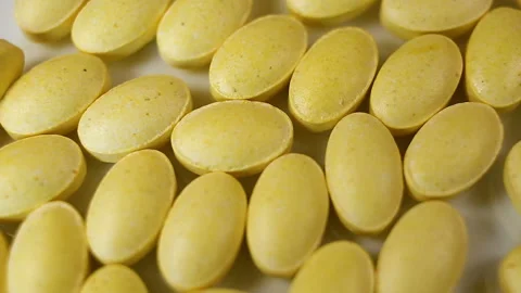 Yellow oval pressed tablets without a shell are thrown down, filling the space. Stock Footage 144854419