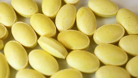 Yellow oval pressed tablets without a shell fall down, filling the space Real ti Stock Footage 144855257