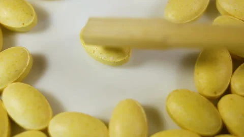 Yellow oval pressed tablets without a shell lie on a white background. Real time Stock Footage 144855407