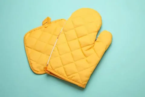 Yellow oven mitts with quilted pattern on blue background Stock Photos
