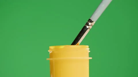 Yellow paint isolated on green background. Gouache falling from paintbrush close Stock Footage 178607031