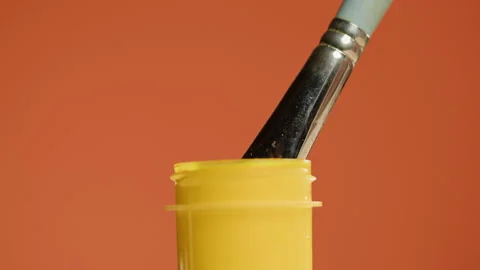 Yellow paint isolated on orange background. Bright gouache falling from Stock Footage 178598505