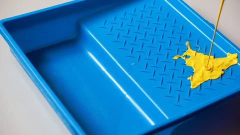 Yellow paint is poured into a blue container Stock Footage 86459925