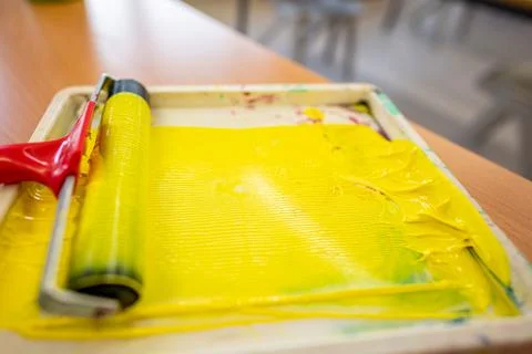 Yellow paint roller in a worker's hand Stock Photos
