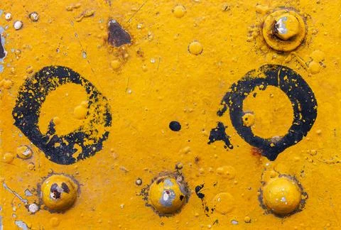 Yellow painted metal surface with rivets, rust, dirt, and black circle pain.. Фото