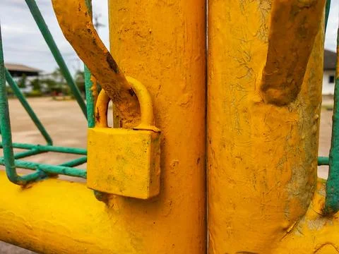 Yellow-painted padlock on the gate Stock Photos
