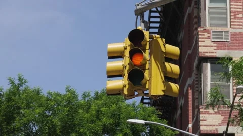 A yellow painted three way intersection traffic light changes from green to Stock Footage 242365891