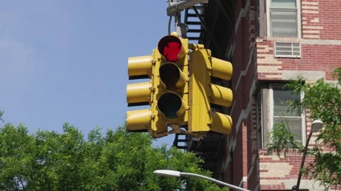 A yellow painted three way stop light hangs in an intersection on a red ligh Stock Footage 242365925
