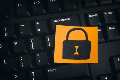 Yellow paper note with closed padlock on a black keyboard Stock Photos