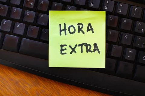 A yellow paper note with hora extra phrase on a black computer keyboard Foto stock