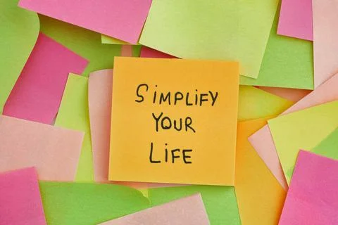 A yellow paper note with the phrase Simplify Your Life written on it with som Stock Photos