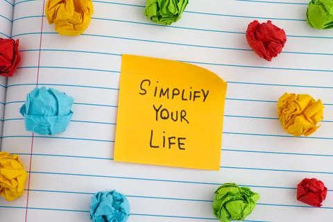 A yellow paper note with the phrase Simplify Your Life on it with some colorf Stock Photos