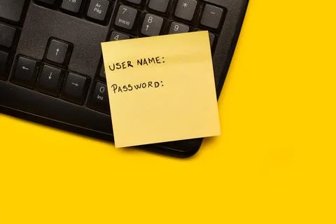 A yellow paper note with user name and password word on a black computer Stock Photos