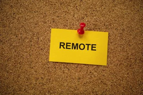 A yellow paper note with the word Remote on it pinned to a cork board. Stock Photos