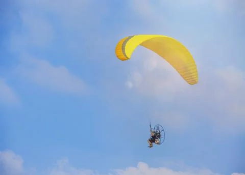 A yellow paraglider with a paramotor, soaring in the rays of the evening sun. 写真素材