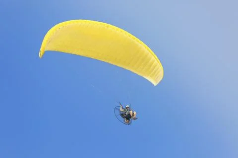 A yellow paraglider with a paramotor, soaring in the rays of the evening sun. 写真素材