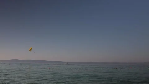 Yellow parasail pulled by speedboat above calm sea during a sunny summer day Stock Footage 341557053