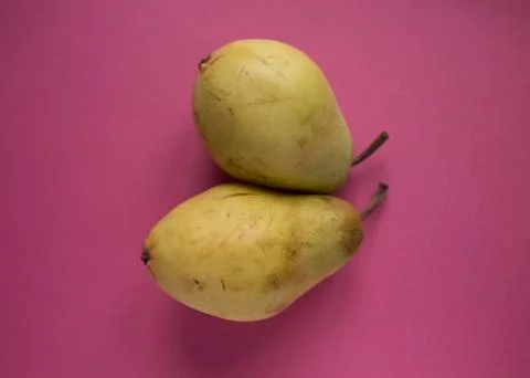 Yellow pears on pink background Stock Photos