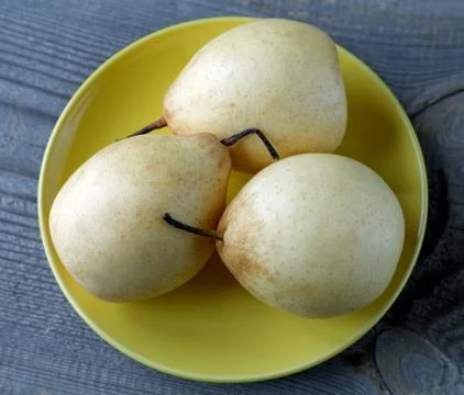 Yellow pears on the plate on a rustic table Stock Photos