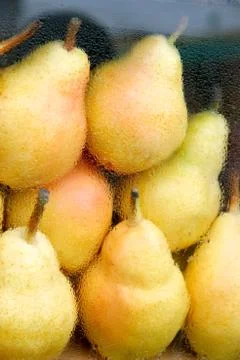 Yellow pears on a store shelf behind glass with drops. Stock Photos