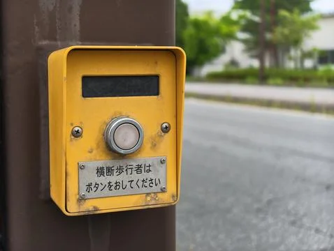 Yellow pedestrian crossing button mounted on pole Stock Photos