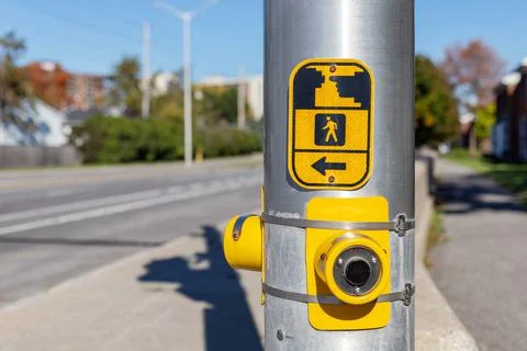 Yellow pedestrian push button on traffic signal pole on the street Stock Photos