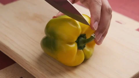 A yellow pepper is being cut in half Stock Footage