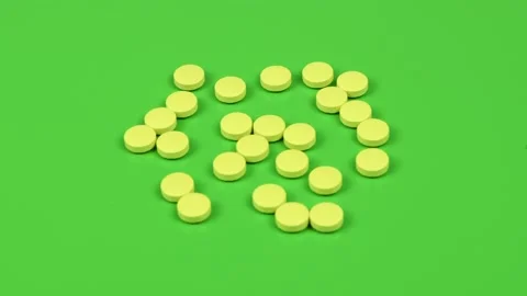 Yellow pills on green background. Side view. Loop motion. Stock Footage 167056378